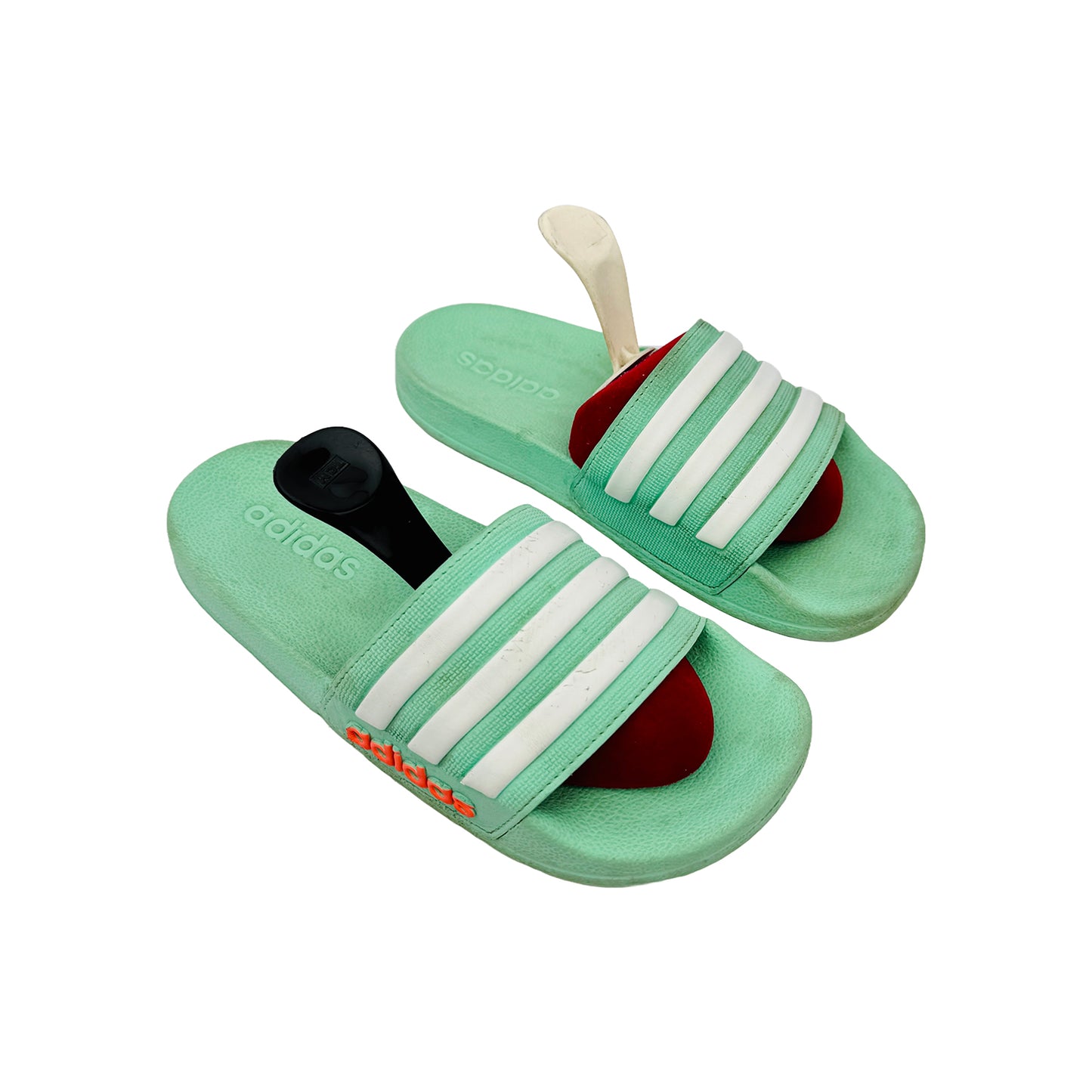 Green Adidas Adilette slides with white stripes on a white background