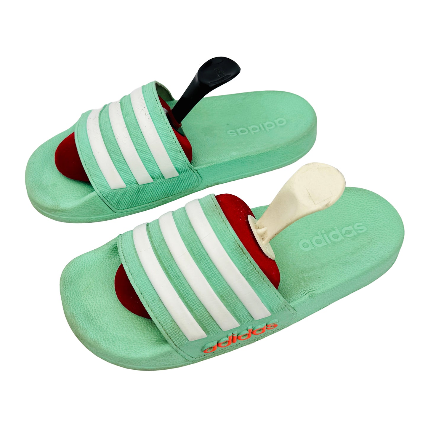 Green Adidas slides with white stripes on a white background