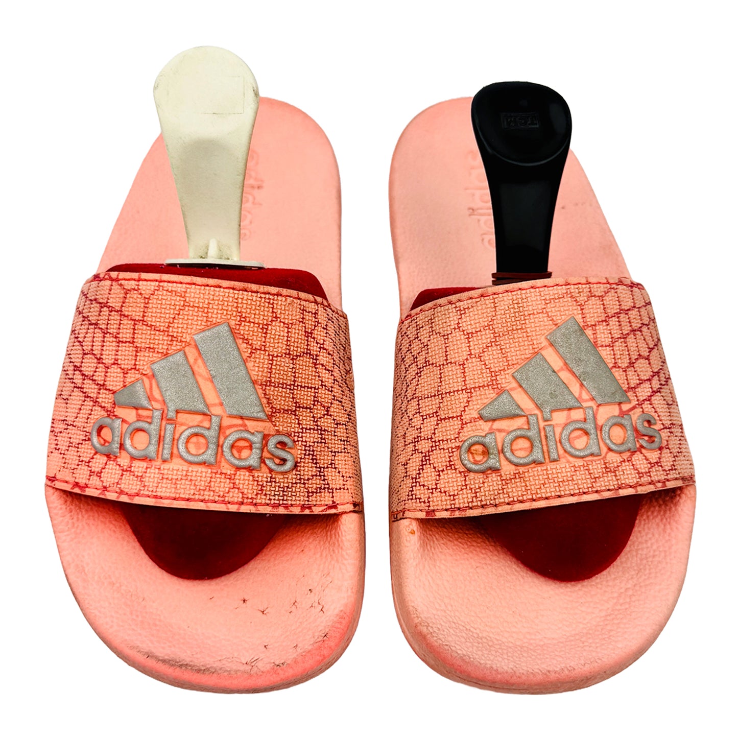 Pair of pink Adidas slides on a white background