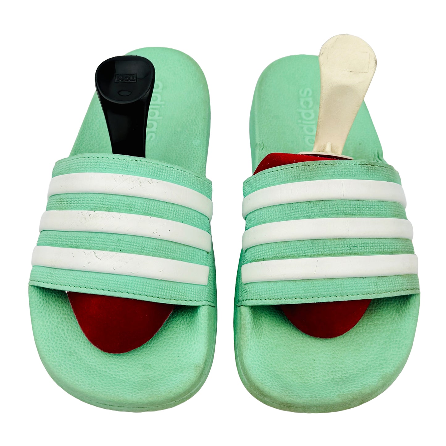 Pair of green adidas slides with white stripes on a white background