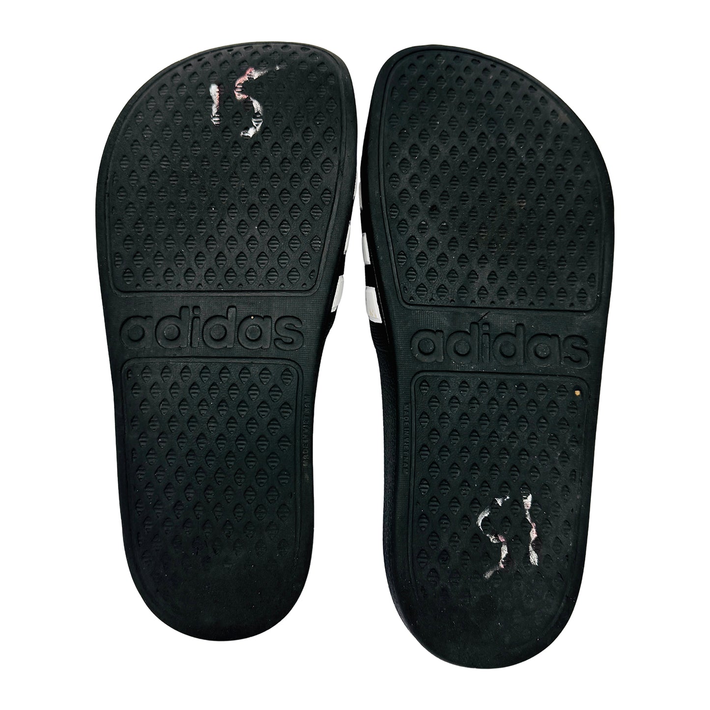 Black Adidas adilette shown from the outsole on a white background