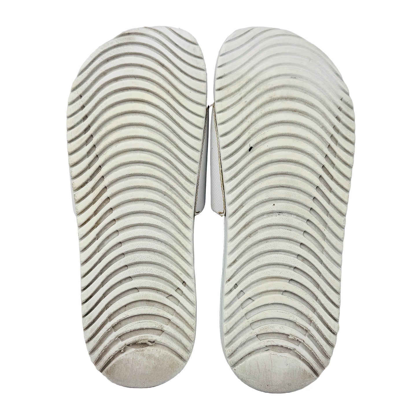 Pair of nike white kawa slides with a wavy pattern on outsole with a white background