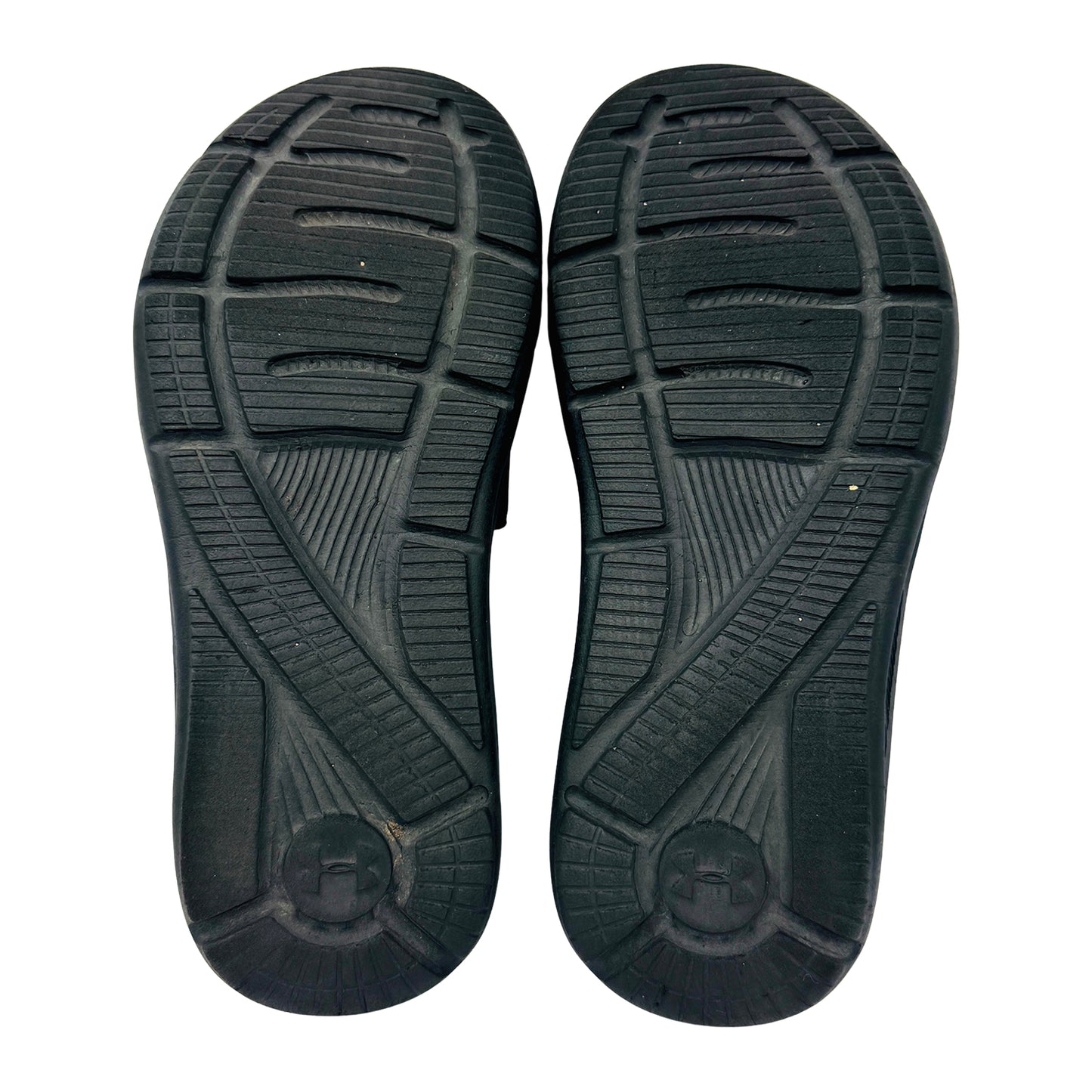 Black rubber outsole of Under Armour slides on a white background