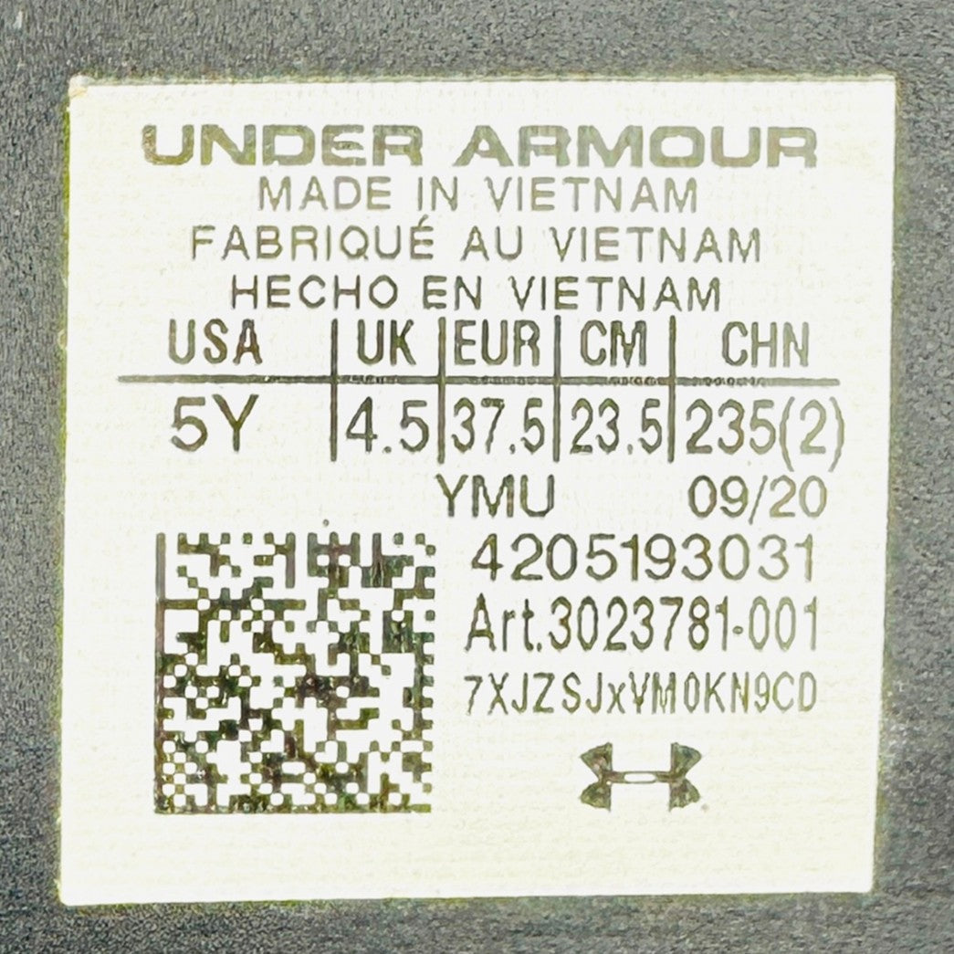 Under Armour label with size, code 3023781-001 and manufacturing information on a gray background