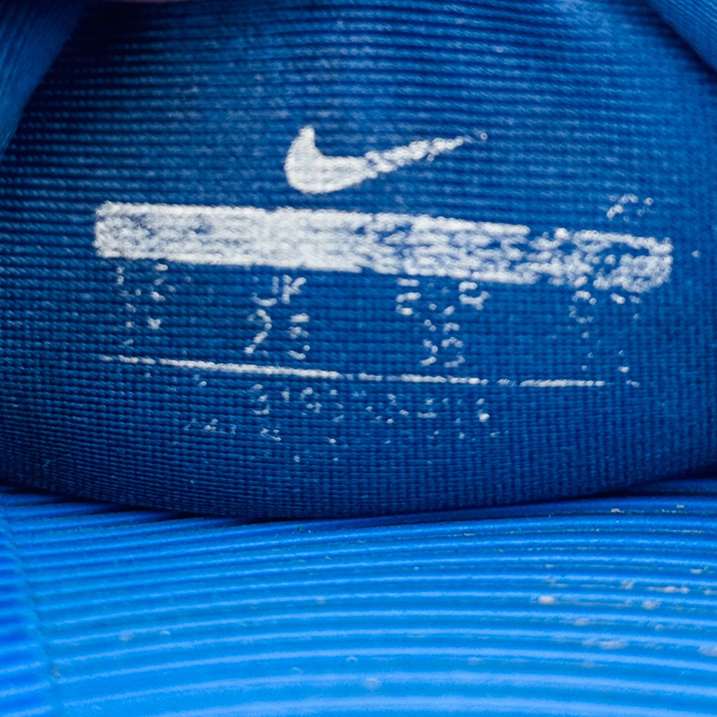 Close-up of a Nike slides label with white logo and text.