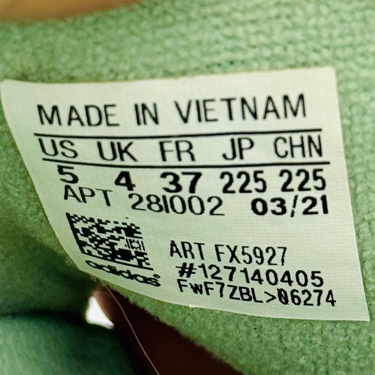 Adidas Adilette Slides Label on a green fabric with text, numbers and code FX5927