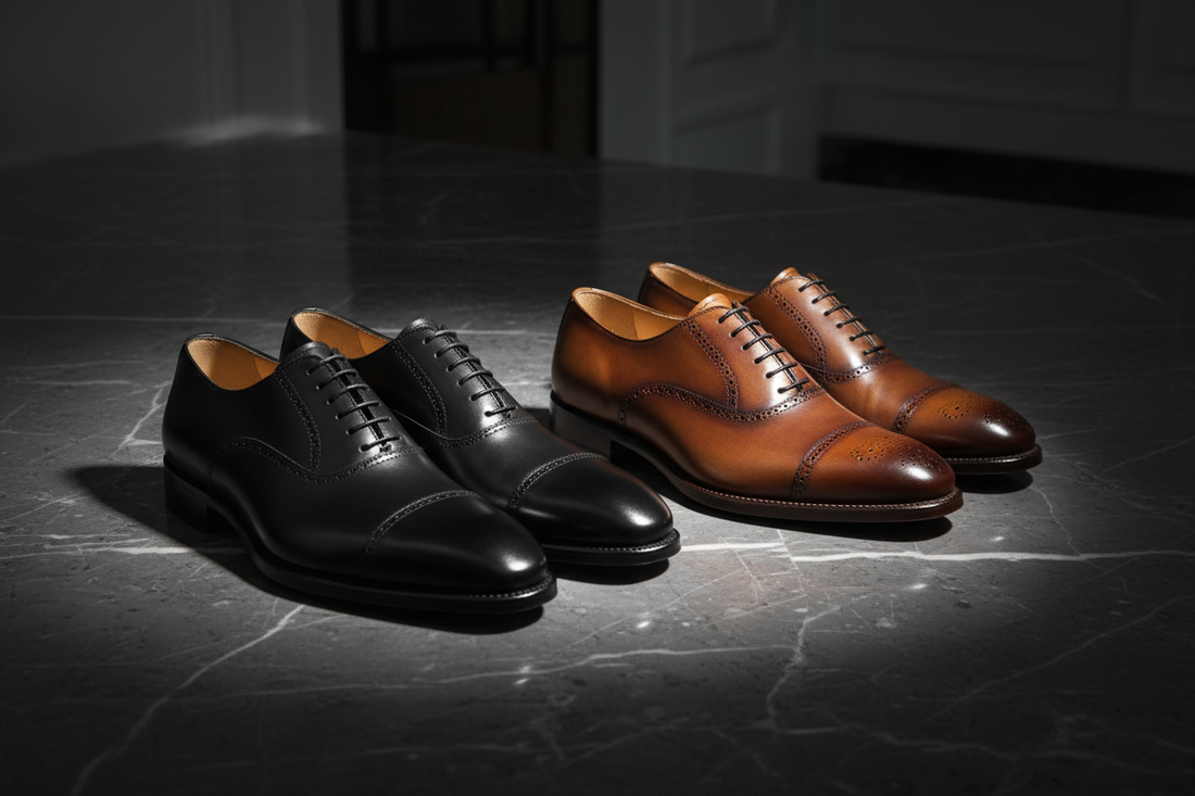 Black Oxford and brown Derby shoes placed side by side on a dark marble surface with dramatic studio lighting