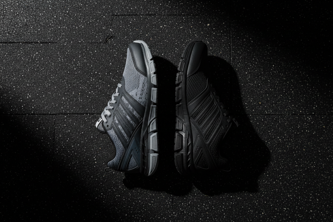Under Armour and Adidas gym training shoes flat lay comparison on dark gym floor