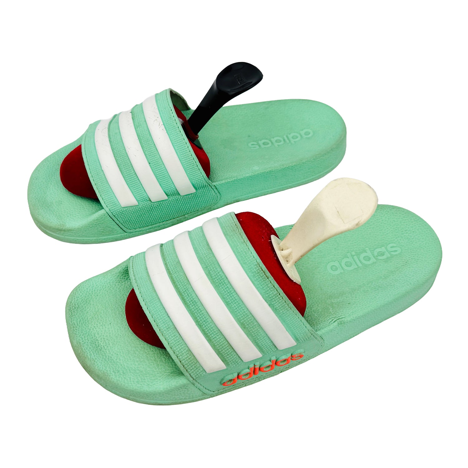 Green Adidas slides with white stripes on a white background
