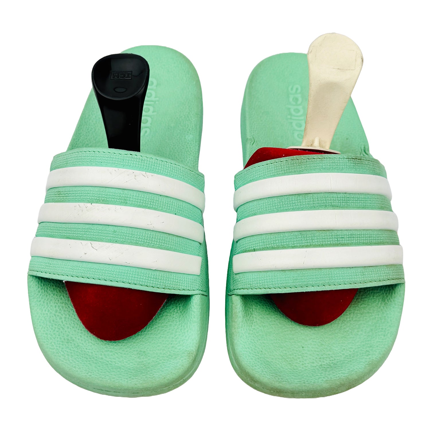 Pair of green adidas slides with white stripes on a white background